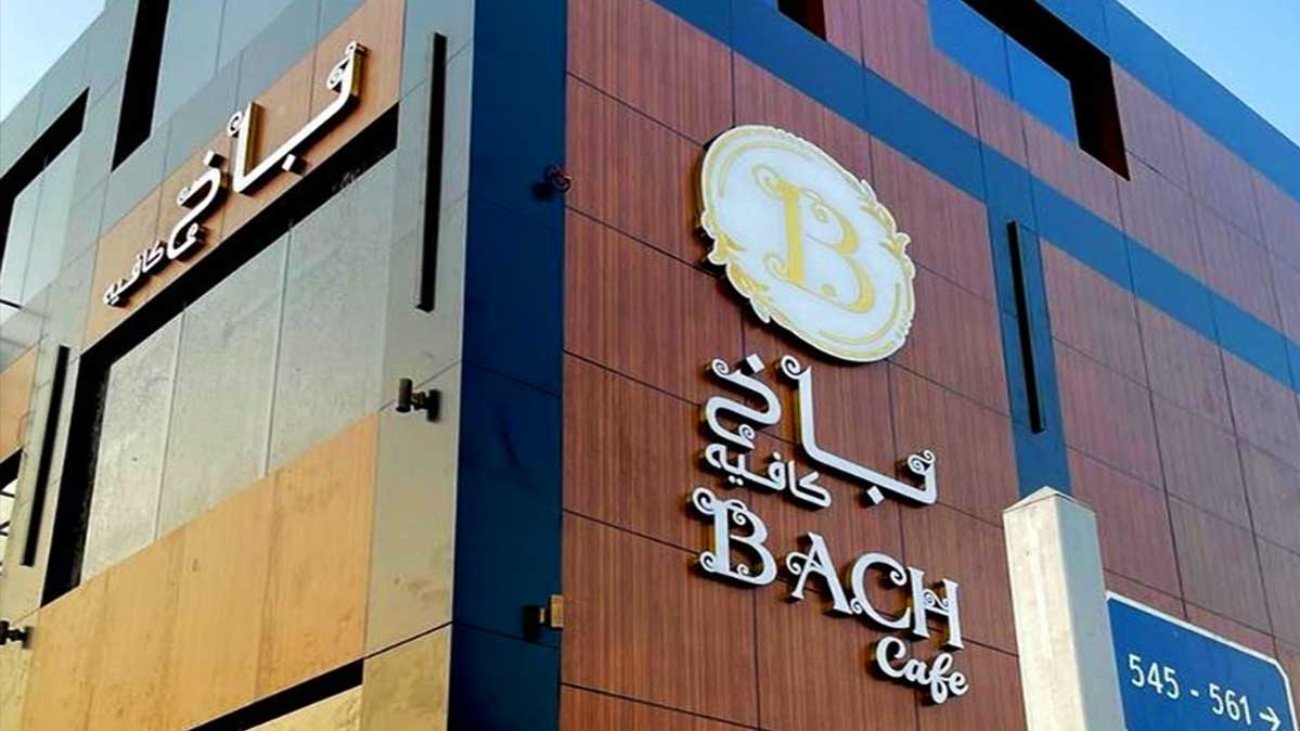 تصميم الواجهات التجارية ثلاثية الأبعاد في السعودية2025 - واجهة تجارية لكافه مصممة باللون البني وفي المنتصف دائرة صفراء موضوع بها حرف B وأسفل الدائرة يوجد كلمة باخ كافيه وأسفلها BACH Cafe